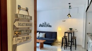 A living room with a sofa, a coffee table, and a wall-mounted sign with directional phrases. - Fenals Family Apartment with Pool (Lloret de Mar)