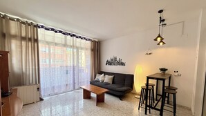 A living room with a sofa, coffee table, and a dining area with stools. - Fenals Family Apartment with Pool (Lloret de Mar)