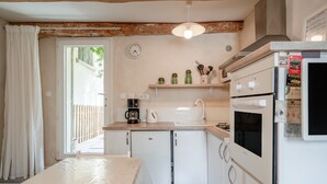 Una cocina con electrodomésticos blancos, un reloj y una ventana con cortinas.