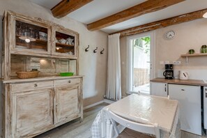 A rustic kitchen with wooden cabinets, a table with a plastic cover, a coffee maker, and a clock on the wall. - Cottage 'Gîte Chez Augustine' with Wi-Fi and Air Conditioning (Sarrians)