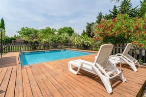 A wooden deck with a swimming pool, white lounge chairs, and a wooden fence. - Cottage 'Gîte Chez Augustine' with Wi-Fi and Air Conditioning (Sarrians)