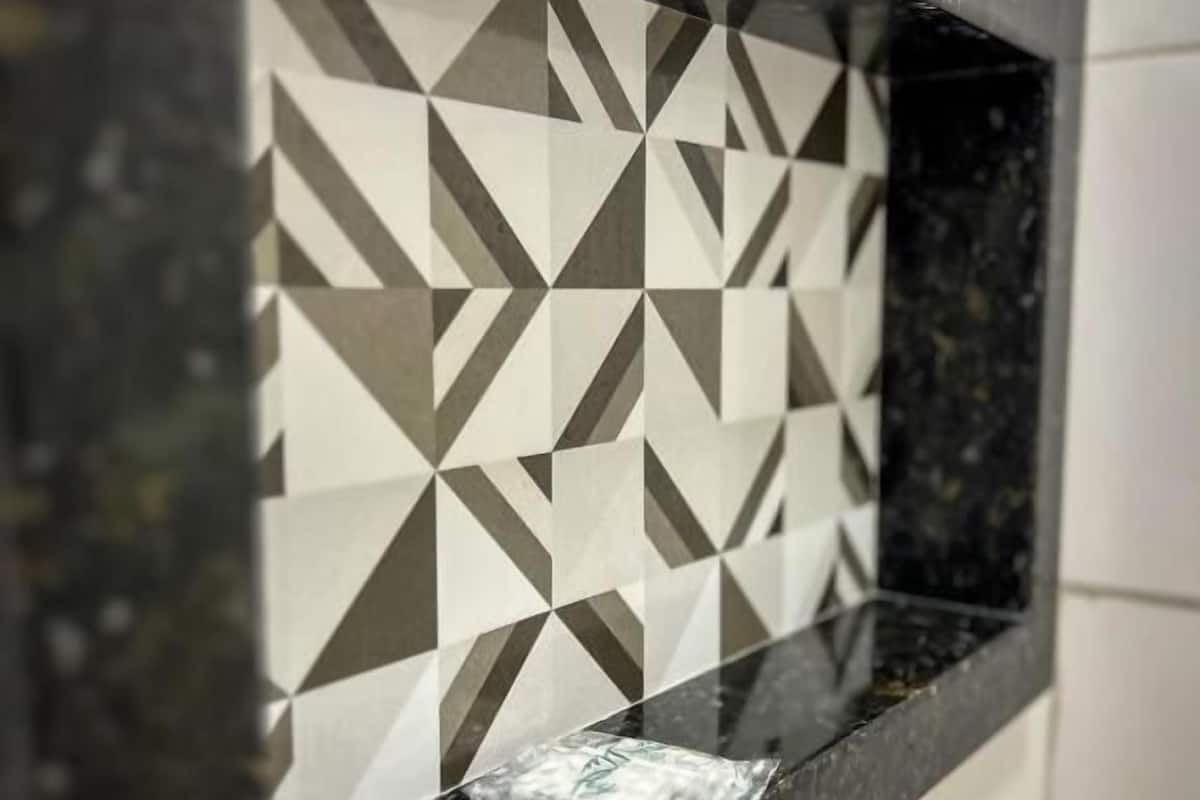 Un baño con encimera negra y un salpicadero de azulejos geométricos.