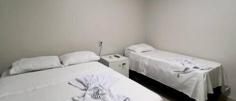 A hotel room with two beds, a nightstand, and a wall socket.