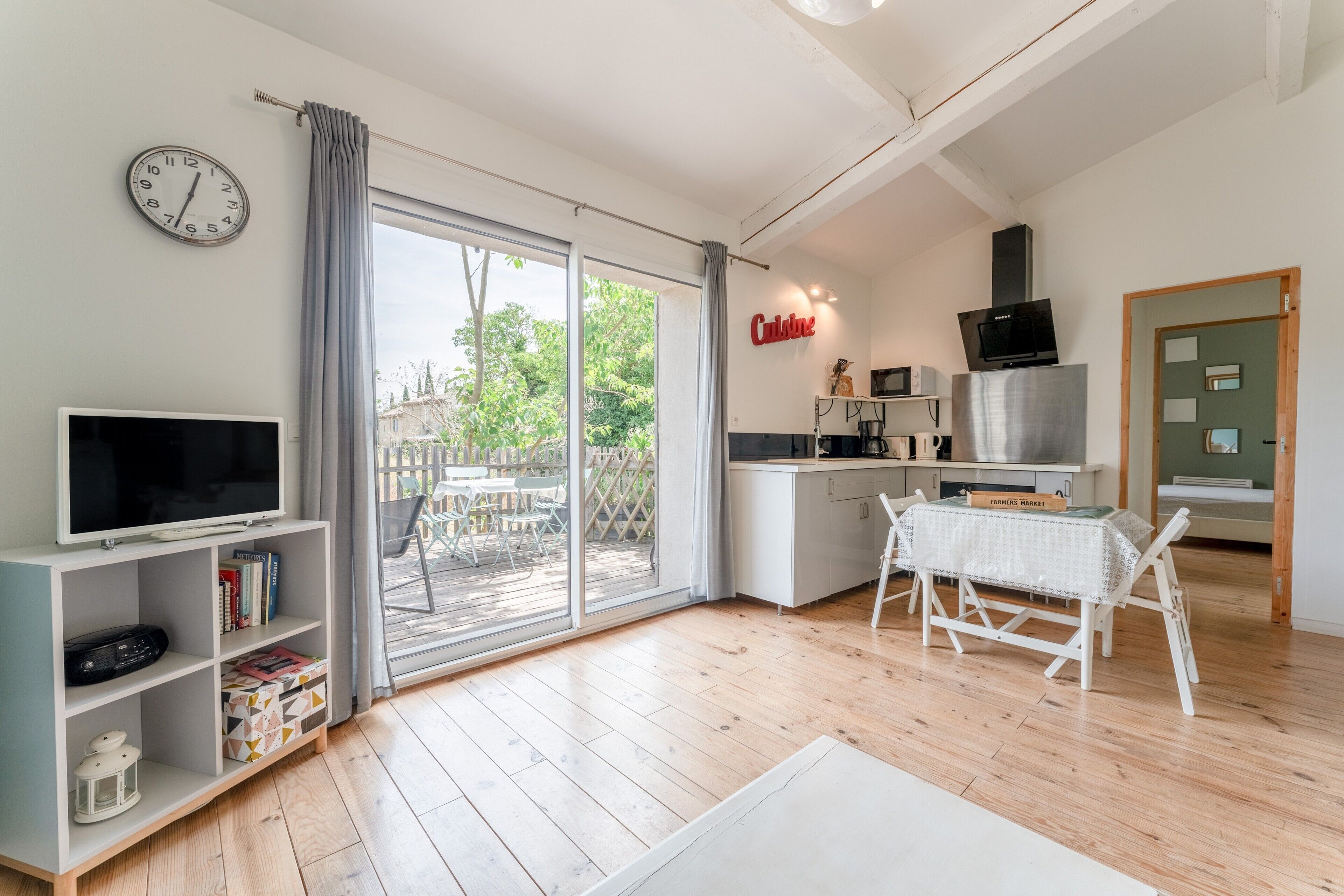 Eine moderne Küche mit Fernseher, Esstisch und Blick durch die Glastür.