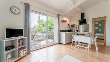 Eine moderne Küche mit Fernseher, Esstisch und Blick durch die Glastür.