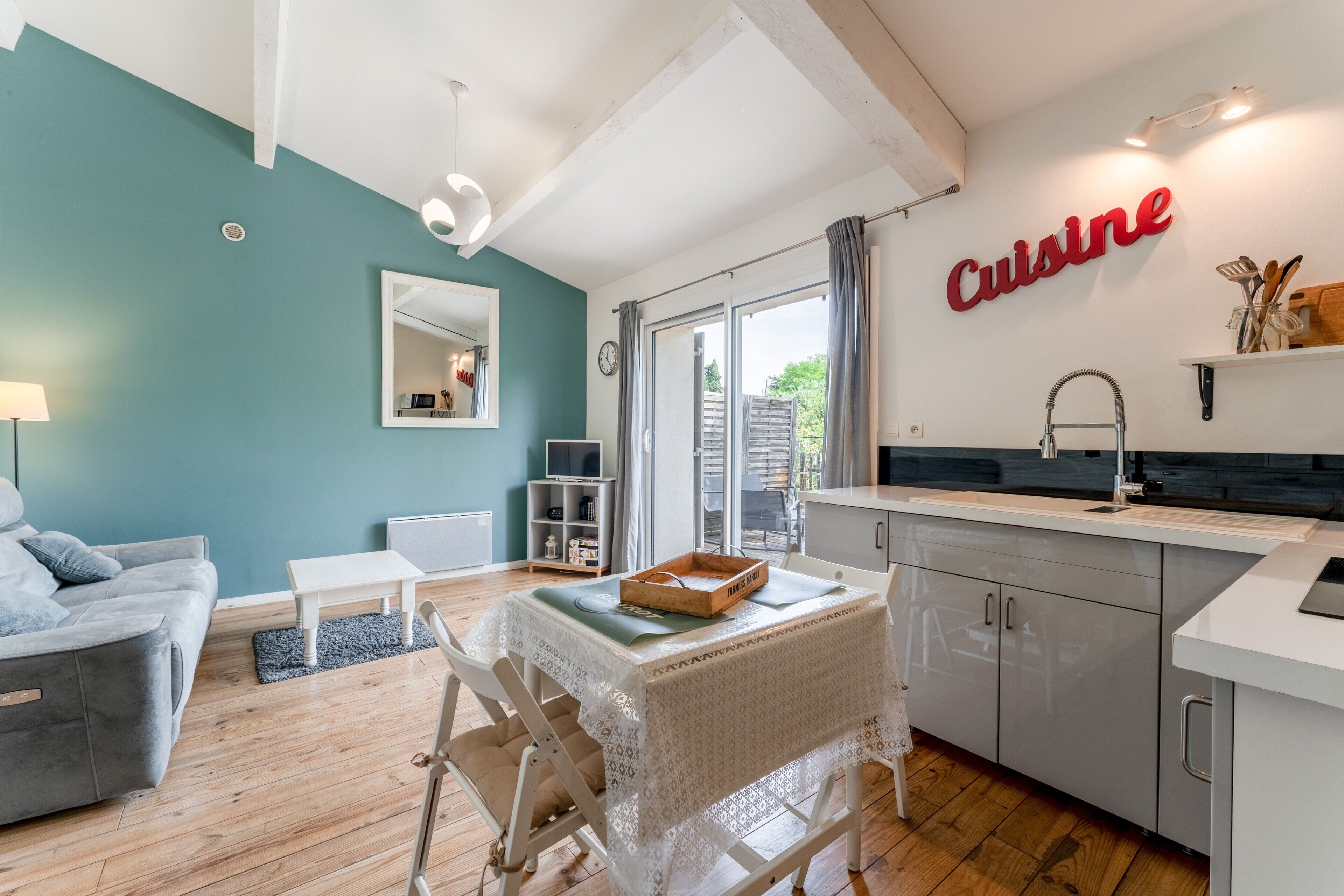 Una cocina moderna con un cartel que dice 'Cuisine', un comedor con una mesa y sillas, y una sala de estar con un sofá y una lámpara.