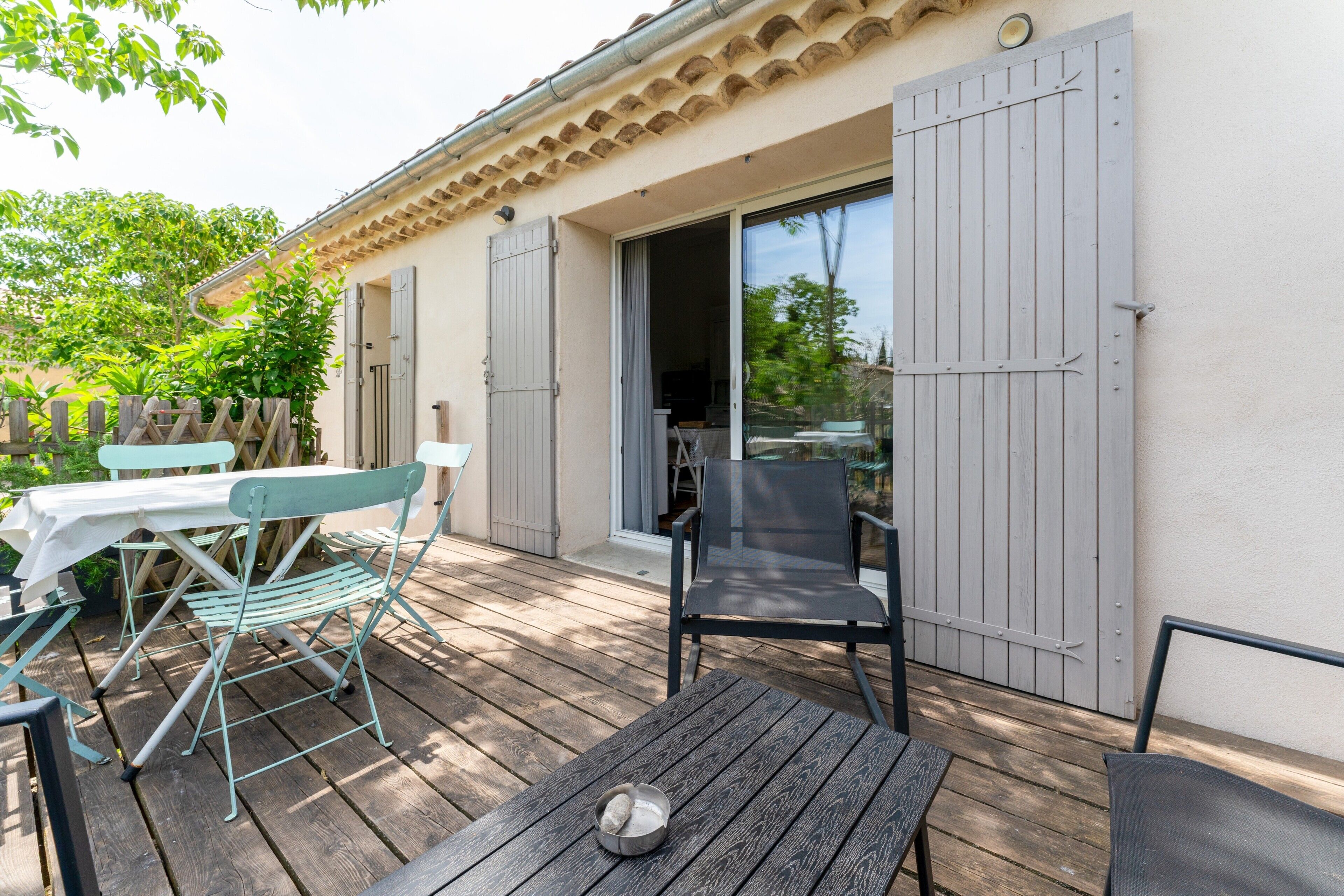 Eine Terrasse im Freien mit Tisch und Stühlen, einer Schiebetür und einem Holzboden.