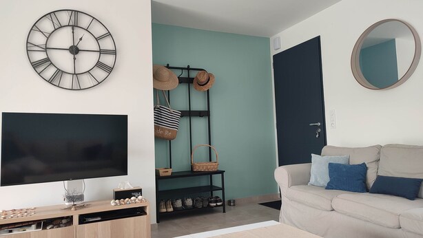 Een woonkamer met een televisie, een klok, een bank, een salontafel en een deur.