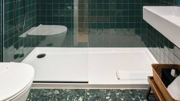 Ein modernes Badezimmer mit einer Glaskabine zur Dusche, einer weißen Badewanne und einem Boden aus Marmorplatten.