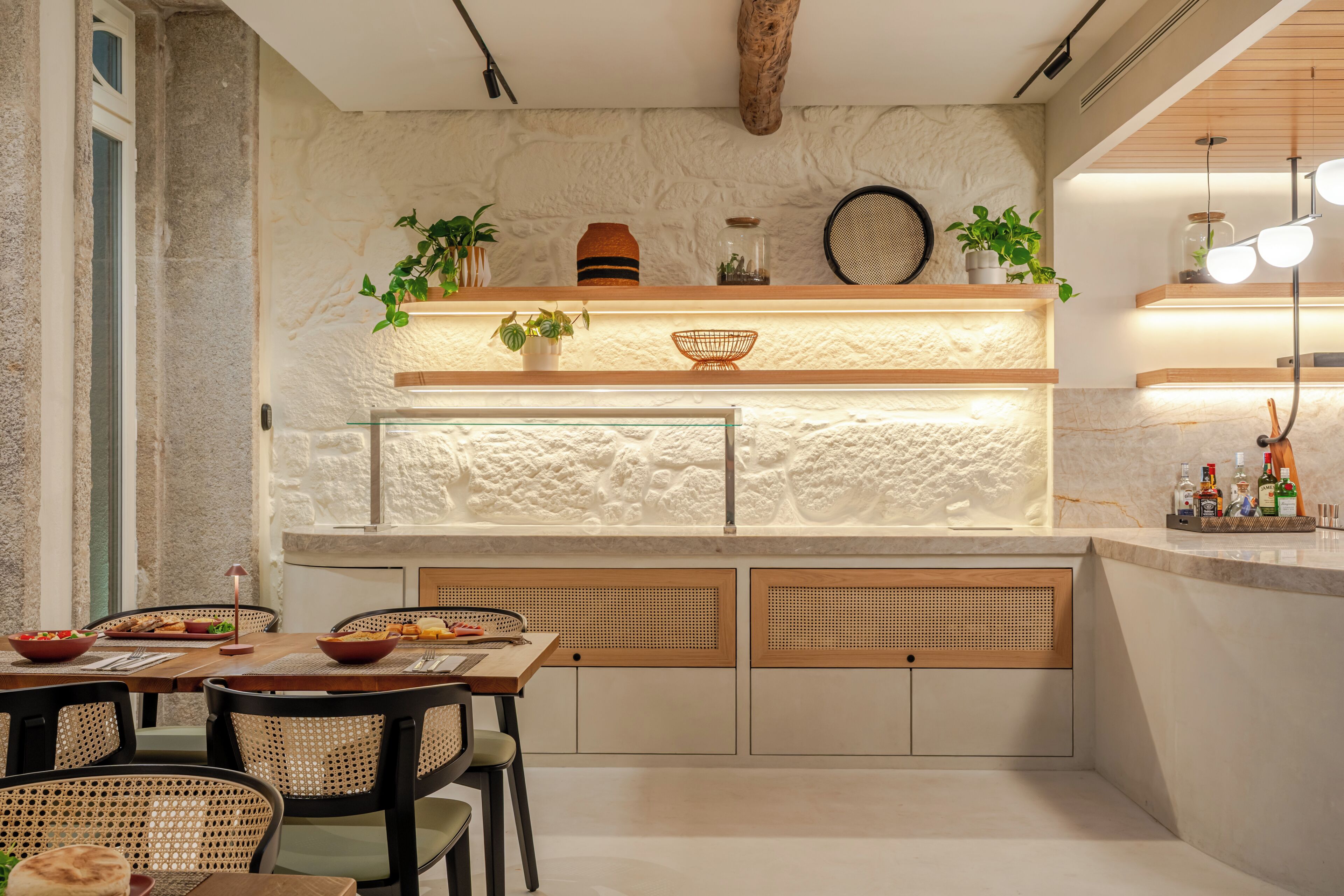 A modern kitchen with a stone wall, wooden cabinets, and a built-in island with seating.