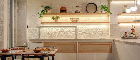 A modern kitchen with a stone wall, wooden cabinets, and a built-in island with seating.