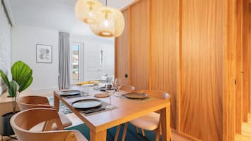 A dining area with a wooden table set for four, two pendant lights, and a potted plant.