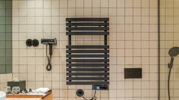 A modern bathroom with a glass shower enclosure, a built-in towel rack, a hairdryer, and a toilet.