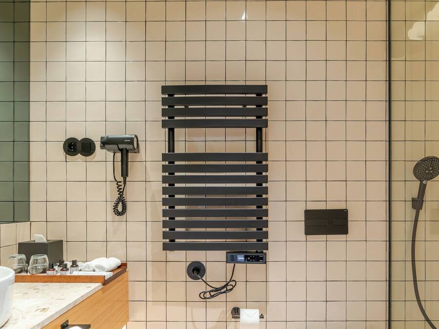 A modern bathroom with a glass shower enclosure, a built-in towel rack, a hairdryer, and a toilet.