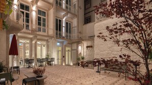 A spacious courtyard with multiple seating areas, a central plant arrangement, and a staircase leading to upper levels. - NOLIA Boutique Hotel (Porto)