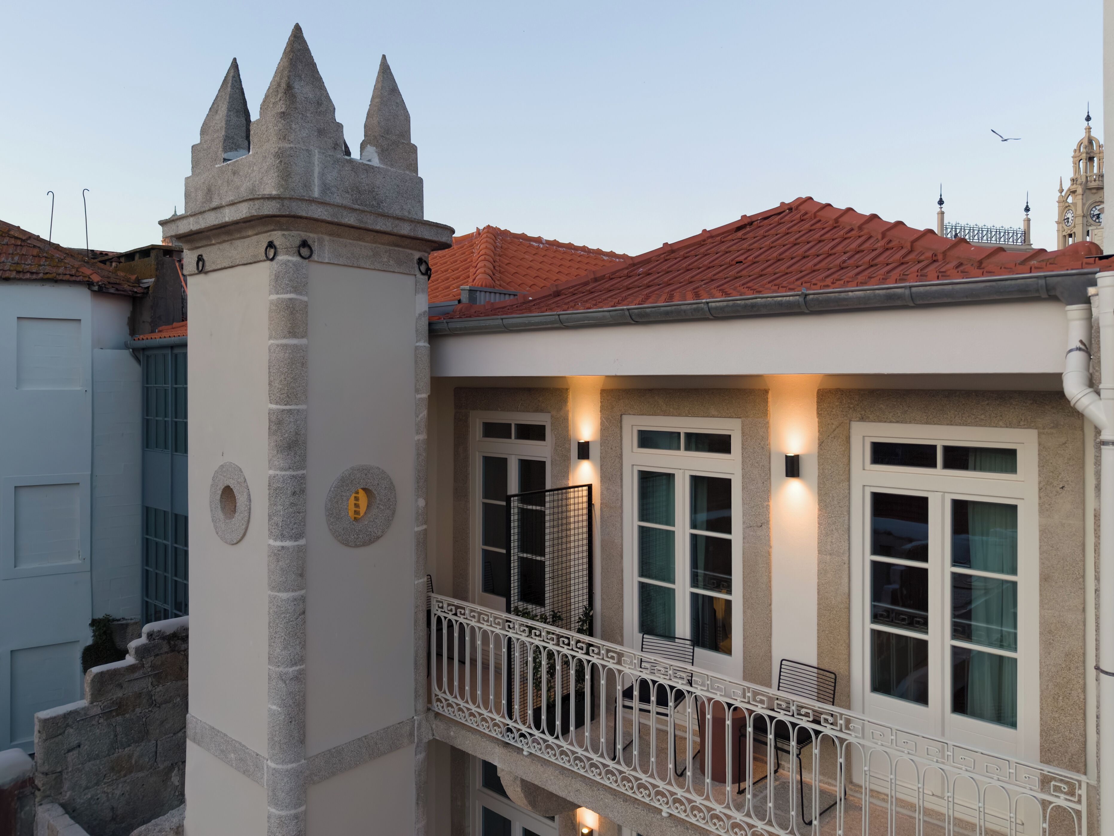 A building with a turret, red-tiled roof, and a balcony with railings.