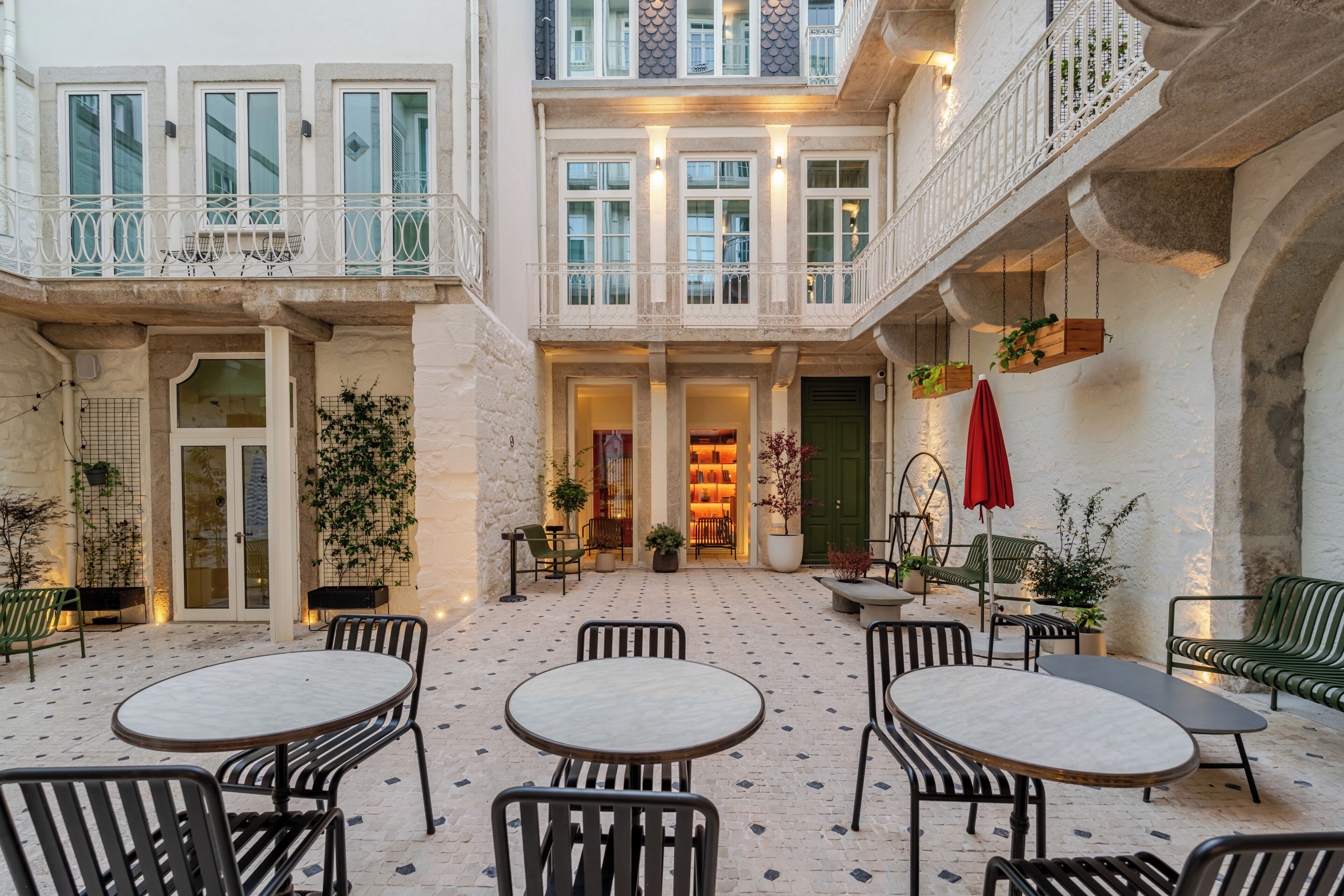 A courtyard with outdoor seating, a central entrance, and a balcony with railings.