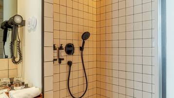 A small, tiled shower area with a handheld showerhead and a wall-mounted shower head.