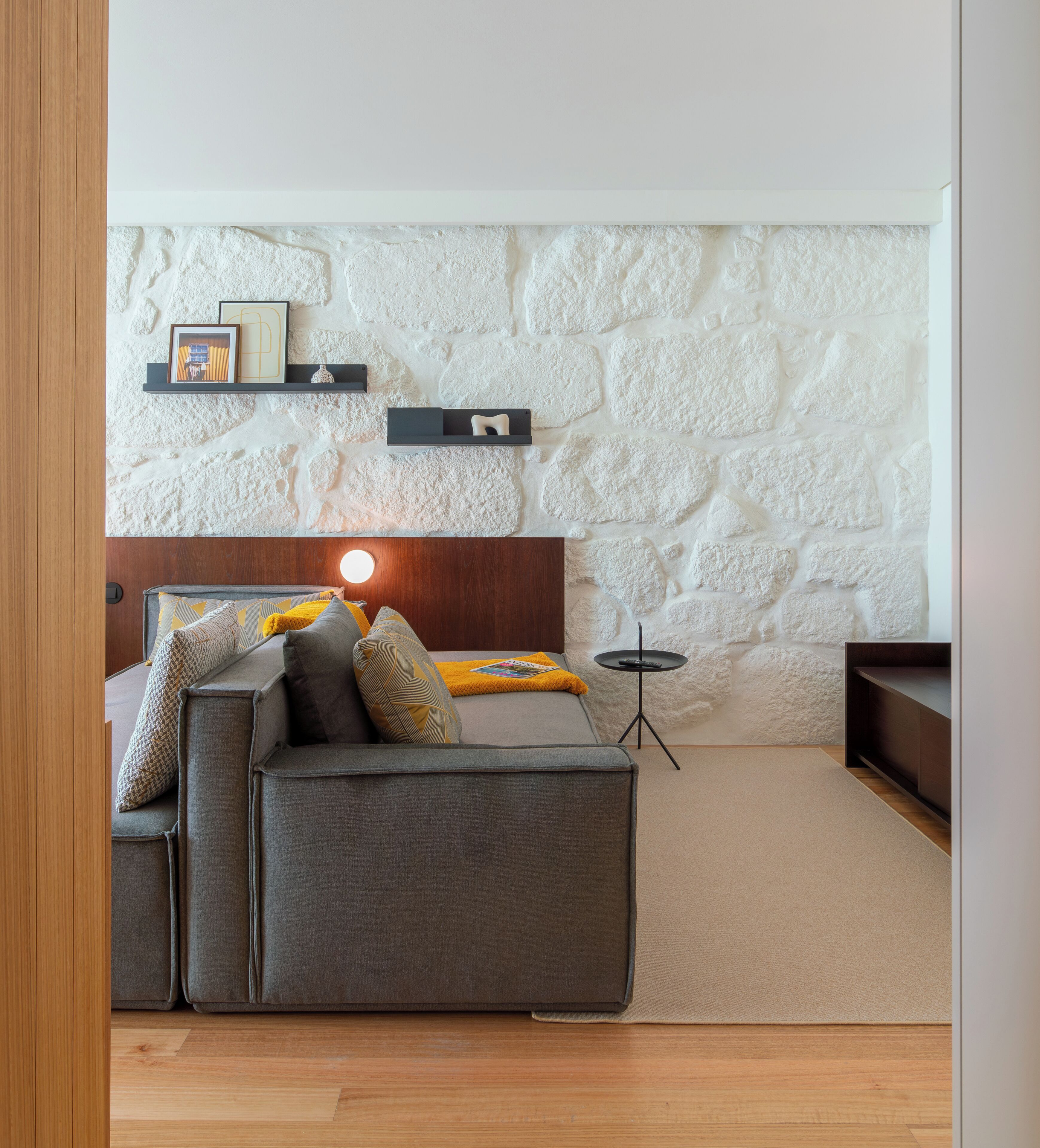 A modern living room with a stone wall, a sofa, a coffee table, and a small side table.