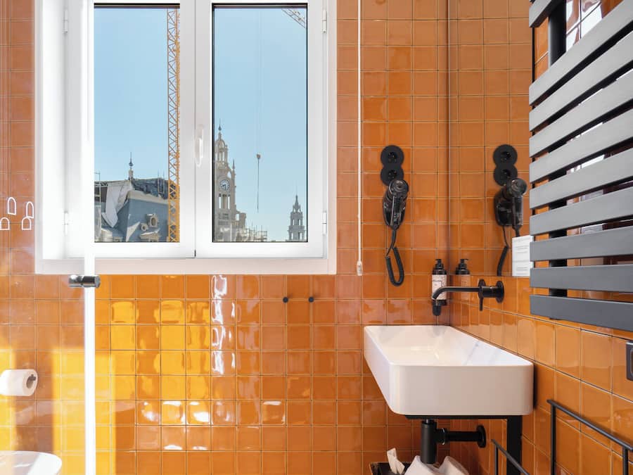 Une salle de bain avec une grande fenêtre, un lavabo et un miroir.