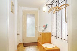 A hallway with a door, a wooden cabinet with a round mirror, and a wall-mounted drying rack. - Vacation apartment 67m2 with DreiWeltenCard - quiet & central in the Black Forest (Bad Dürrheim)