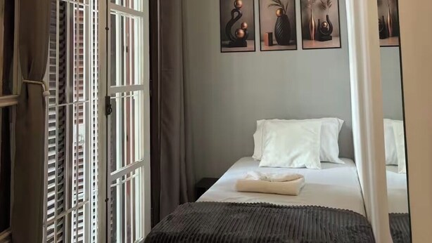 A bedroom with a bed, a window with blinds, a door with a curtain, and wall art. - Entire Mansion 278 in Morumbi | Luxury, Comfort and Privacy (Morumbi)