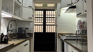 A kitchen with white cabinets, a black door, and a chandelier. - Entire Mansion 278 in Morumbi | Luxury, Comfort and Privacy (Morumbi)