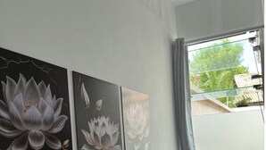 A room with a bed, a window with a view of greenery, and three wall-mounted floral paintings. - Entire Mansion 278 in Morumbi | Luxury, Comfort and Privacy (Morumbi)