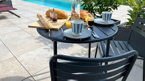 Ein Patio-Tisch mit Frühstücksleckereien, einer Karaffe und einem Pool im Hintergrund.