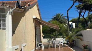 Ein Gebäude mit Ziegeldach, einer überdachten Terrasse mit Sitzgelegenheiten und einem Kiesgrundstück.