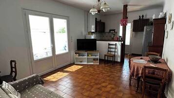 Une pièce comprenant un canapé, une table à manger avec des chaises, un coin cuisine avec des placards, un réfrigérateur et un ventilateur de plafond.