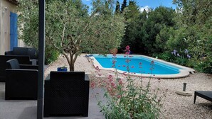 Um quintal com piscina, móveis de jardim e uma pérgola.