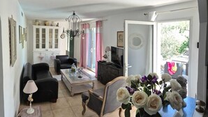 Uma sala de estar com sofá, mesa de centro, televisão e lustre.