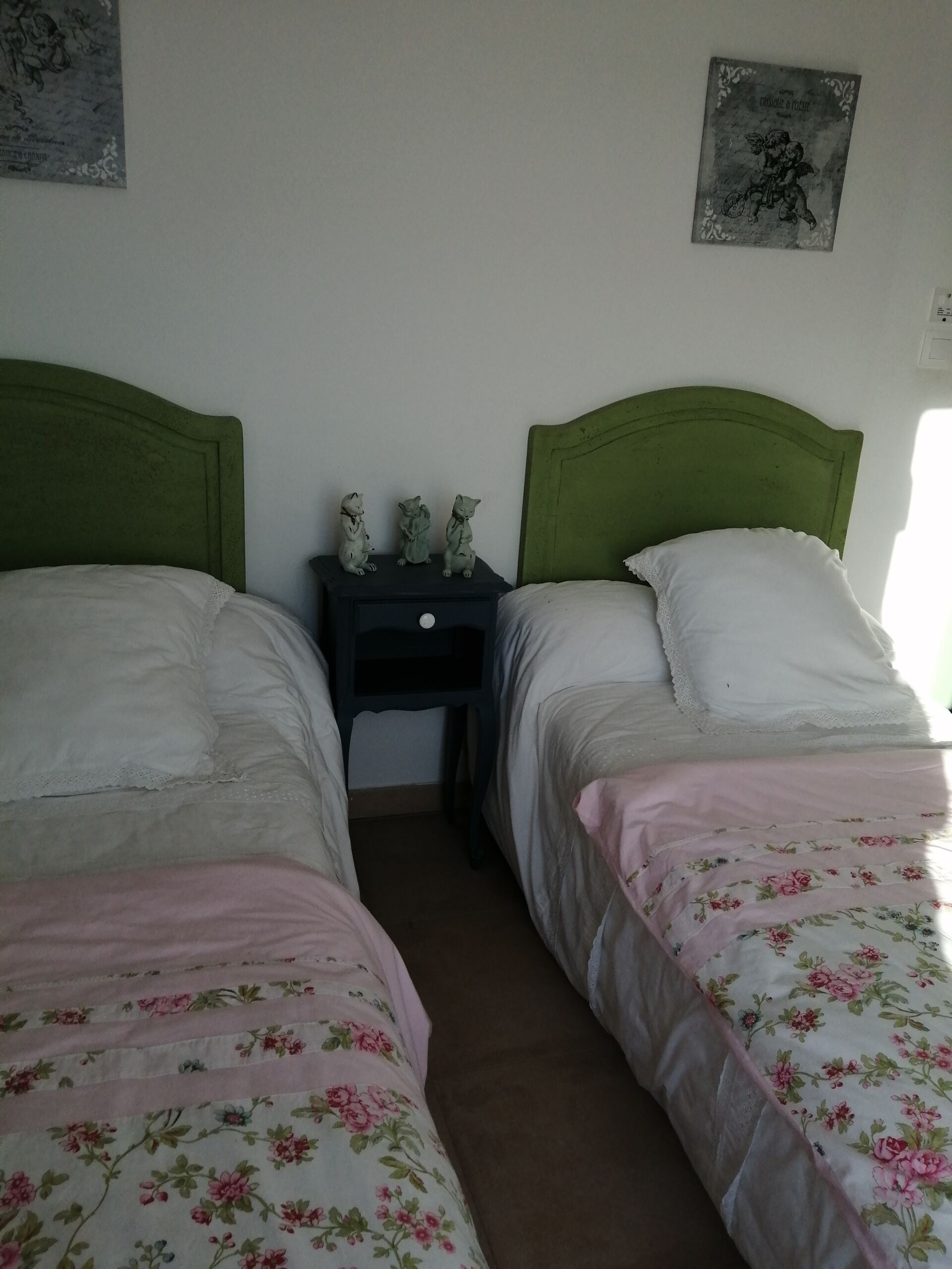 A room with two beds, a nightstand, and a wall-mounted picture.