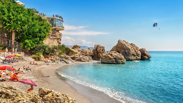 A beach with clear blue water, rocky formations, and a viewing platform. - Azure Apartment Burriana by At Home Costa del Sol (Nerja)