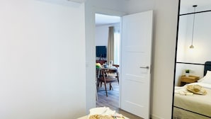 A hotel room with a bed, bedside table, and a view into the dining area. - Azure Apartment Burriana by At Home Costa del Sol (Nerja)