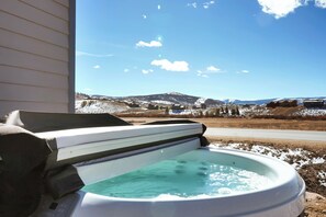 Ein Whirlpool mit Blick auf eine verschneite Landschaft und Berge.