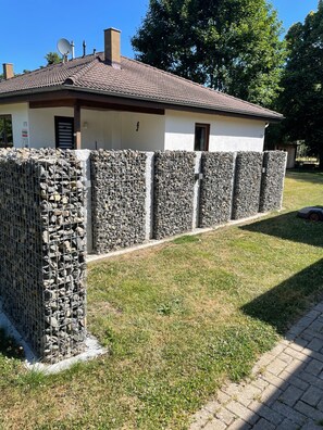 En byggnad med ett tak täckt av tegelpannor, en stenmur och en gräsyta.