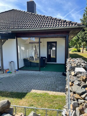 Un bâtiment doté d’un toit en tuiles, d’un patio couvert et d’une entrée pavée.
