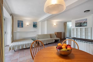 A room with a dining table, a sofa, a radiator, and a window with curtains. - Villa 'Pia Recco' with Sea View, Private Pool and Wi-Fi (Recco)