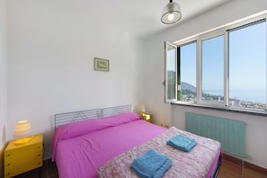 A bedroom with a bed, a nightstand, a window with a view, and a radiator. - Villa 'Pia Recco' with Sea View, Private Pool and Wi-Fi (Recco)