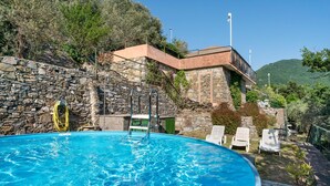 A swimming pool with stone walls, a stone staircase, and a view of a hillside.