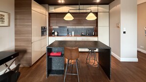 Una cucina moderna con isola centrale, illuminazione a sospensione e uno sgabello da bar.