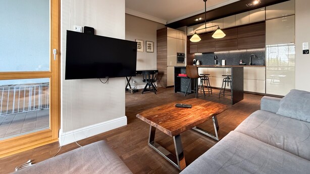 Un soggiorno moderno con una televisione a schermo piatto, un tavolino in legno e un divano grigio.