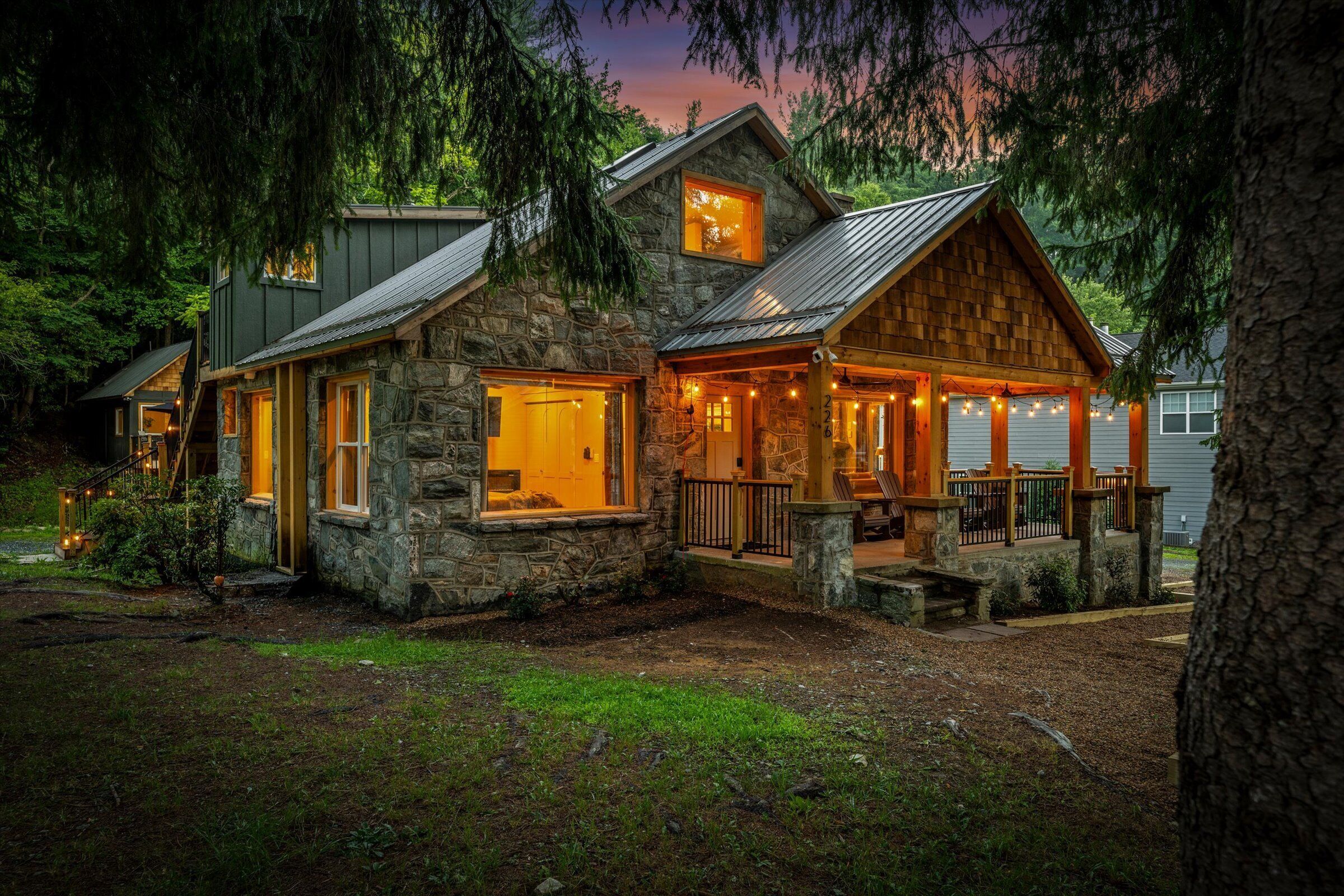 Una casa de piedra con porche, escaleras y vistas al bosque circundante.