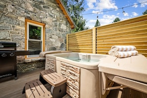 A stone exterior wall, a wooden deck, a hot tub, and a grill. - StoneHouse Suites | 4Bd/3Bth Home | Pet Friendly (Banner Elk)