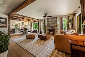 A spacious living area with a stone fireplace, a dining area, and a kitchen in the background. - StoneHouse Suites | 4Bd/3Bth Home | Pet Friendly (Banner Elk)