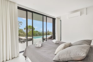 A bedroom with a large bed, a view of a pool, and a sliding glass door. - Villa with Spectacular Sea Views and Private Infinity Pool (Begur)
