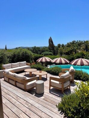 A wooden deck with outdoor furniture, including a sofa and chairs, and striped umbrellas. - Villa LoKa - 5 bedrooms, swimming pool - Gulf of Saint-Tropez (Grimaud)