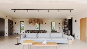 Ein geräumiges Wohnzimmer mit einem hellen Sofa, einem Holztisch und einem Essbereich mit Tisch und Stühlen.